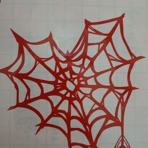 Op de afbeelding: Rood spinnenweb met een spin die aan de onderkant hangt. Het web is een eenvoudig ontwerp met een centrale hub en stralende lijnen.