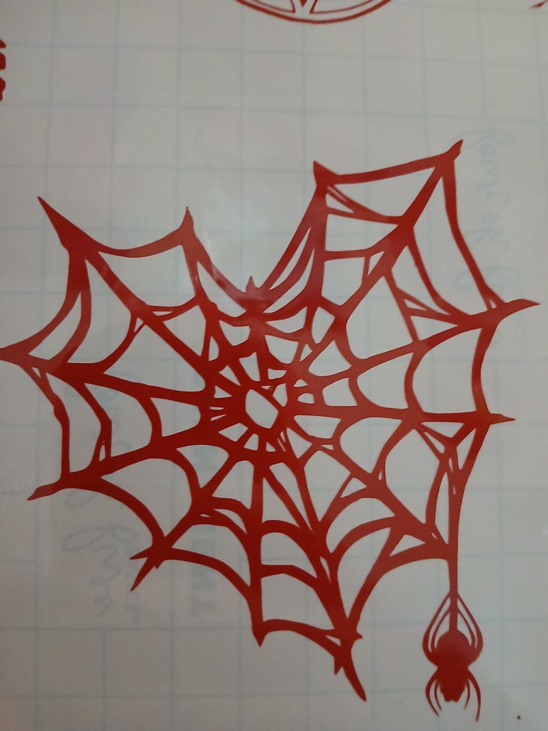 Op de afbeelding: Rood spinnenweb met een spin die aan de onderkant hangt. Het web is een eenvoudig ontwerp met een centrale hub en stralende lijnen.