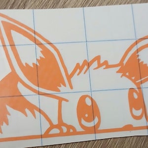 Puede incluir: Pegatina de vinilo naranja con un diseño de zorro de dibujos animados. El zorro tiene orejas grandes y una cara sonriente, asomándose por un borde. La pegatina está sobre un fondo blanco con un patrón de cuadrícula.