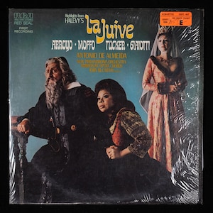 May include: A vintage vinyl record cover for the opera La Juive by Halevy. The cover features a photo of three opera singers, two women and one man, in costume. The text on the cover reads "La Juive" and "Highlights from Halevy's La Juive".
