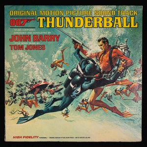 May include: A vintage record album cover featuring James Bond, the iconic secret agent, in a scuba diving scene. The album cover is for the 007 film "Thunderball" with the title song sung by Tom Jones. The album cover is a vibrant blue and green with a yellow and red title.