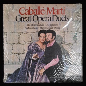 May include: A vintage vinyl record album cover featuring a photo of two opera singers, a woman and a man, in costume. The album title is "Caballé Martí Great Opera Duets" and lists the operas "Un Ballo in maschera, Les Huguenots, Andrea Chénier, Manon Lescaut, Poliuto".