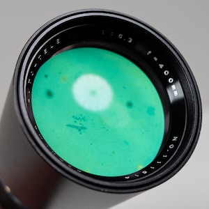 May include: A black AUTO-TELE lens with a green interior. The lens has the specifications f=400mm and 1:6.3. The lens also has the number 11814.
