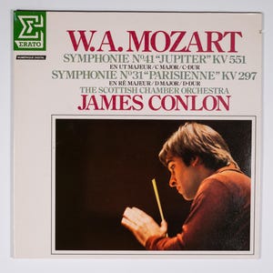 May include: A vintage vinyl record album cover featuring a photo of a conductor with a baton in hand. The album is titled "W.A. Mozart" and features the symphonies "Jupiter" (KV 551) and "Parisienne" (KV 297) performed by the Scottish Chamber Orchestra conducted by James Conlon.