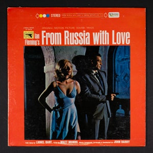 May include: A red vinyl record album cover with a photo of James Bond and a woman in a blue dress. The album title is "From Russia with Love" and the text "James Bond is Back" is at the top of the cover. The album is a soundtrack to the movie "From Russia with Love".