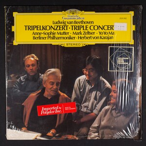 May include: A vinyl record album cover featuring a group of musicians. The album is titled "Tripelkonzert Triple Concert" by Ludwig van Beethoven. The musicians are Anne-Sophie Mutter, Mark Zeltser, YoYo Ma, and Herbert von Karajan. The album is a Deutsche Grammophon recording.