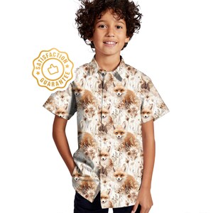May include: A white short-sleeved button-down shirt with a fox print. The shirt has a brown and white fox pattern with a white background. The shirt has a collar and a button closure.