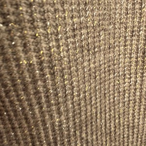 May include: Close-up of a brown knitted fabric with gold glitter woven throughout.