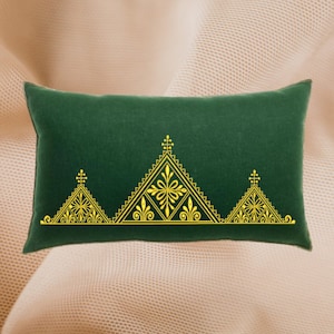 Könnte beinhalten: Ein grünes Samtkissen mit einem goldenen, gestickten geometrischen Muster. Das Muster zeigt drei Dreiecke mit filigranen Details.