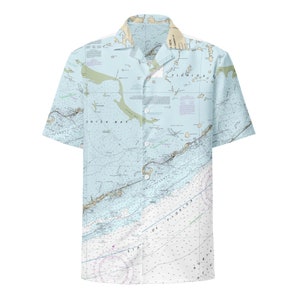 May include: A light blue short-sleeved button-down shirt with a nautical map print. The map shows the Florida Keys and Dry Tortugas. The shirt has a collar and a button closure.