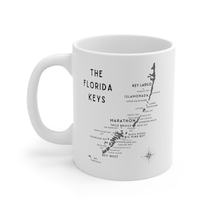 May include: White ceramic mug with a black and white illustration of the Florida Keys. The mug features the names of the islands and a compass rose.