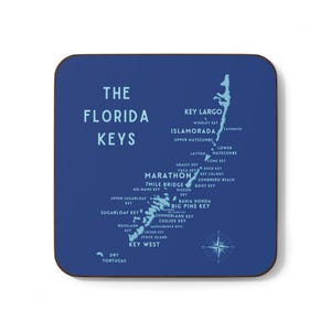 May include: Square coaster with a map of the Florida Keys. The coaster is navy blue with light blue text and a compass rose. The text includes the words "The Florida Keys" and the names of the keys.