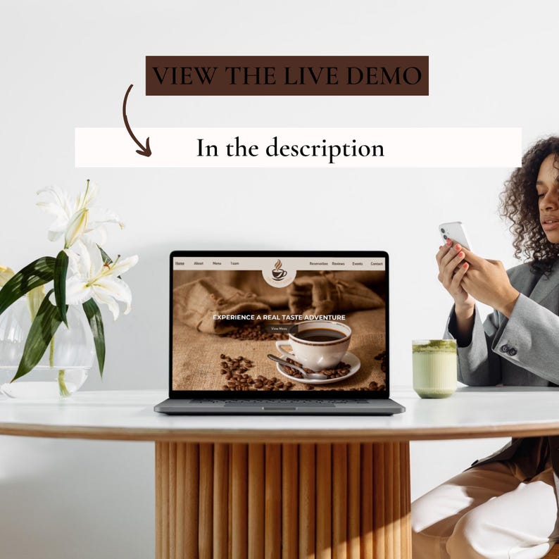 May include: A laptop computer open to a website with the text "Experience a real taste adventure" and a picture of a cup of coffee. The laptop is on a wooden table with a white surface. A person is holding a smartphone in their right hand and a cup of green tea in their left hand.