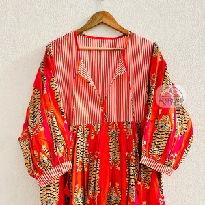 Könnte beinhalten: Ein langes, rot-weiß gestreiftes Kleid mit Tigerdruck. Das Kleid hat einen V-Ausschnitt und 3/4 Ärmel. Das Kleid ist aus Baumwolle und perfekt für den Sommer.