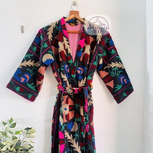 May include: A black robe with colourful floral embroidery. The robe has a tie belt and a striped lining. The text "JAIPUR HAND STUDIO" is visible on the robe.