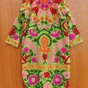 May include: A long green cotton robe with colourful floral embroidery. The robe has a mandarin collar and long sleeves. The embroidery is in shades of pink, red, orange, and green.