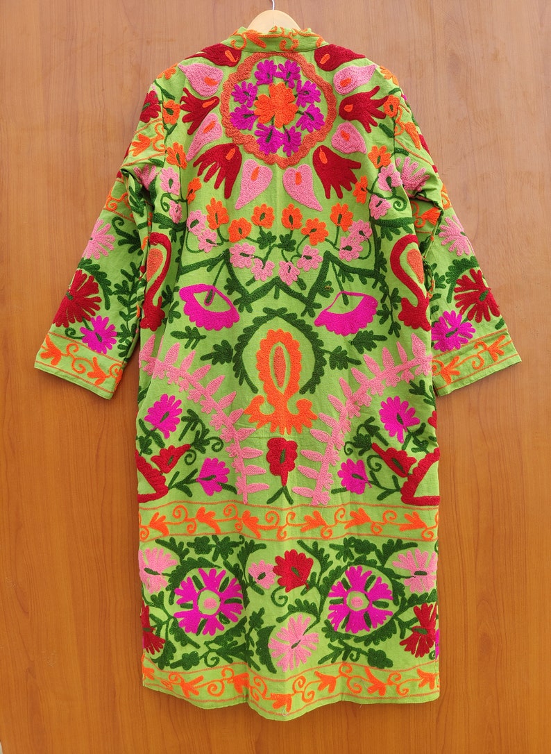 May include: A long green cotton robe with colourful floral embroidery. The robe has a mandarin collar and long sleeves. The embroidery is in shades of pink, red, orange, and green.