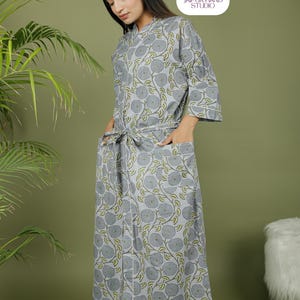 Puede incluir: Una bata gris con estampado floral, ribete blanco y lazo a juego. La bata tiene mangas tres cuartos y bolsillos. El logotipo de Jaipur Hand Studio est&aacute; en la esquina superior derecha.