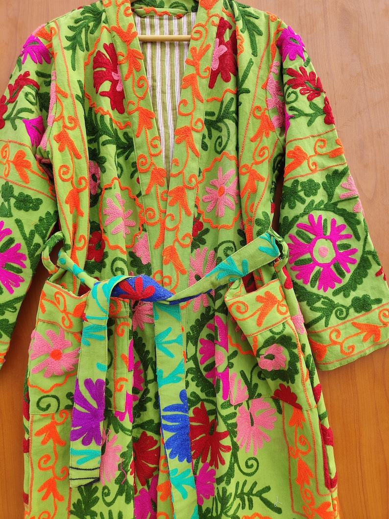 May include: A green robe with colourful floral embroidery. The robe has a tie belt and long sleeves.
