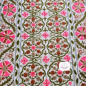 May include: White cotton throw blanket with intricate embroidery in shades of pink, brown, and green. The design features repeating floral motifs and a central logo that reads "Jaipur Hand Studio".