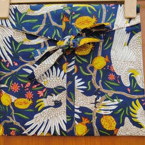 May include: A blue fabric with a white bird and floral pattern. The fabric has a white ribbon tied around it.