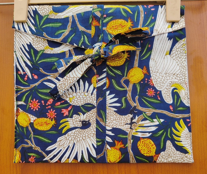 May include: A blue fabric with a white bird and floral pattern. The fabric has a white ribbon tied around it.