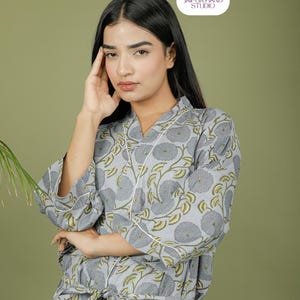 Puede incluir: Bata con estampado floral gris claro con ribete blanco. La bata presenta una cintura anudada y un dise&ntilde;o de cuello en V. El estampado floral incluye flores grises y hojas verdes. La bata est&aacute; hecha de una tela suave y ligera.