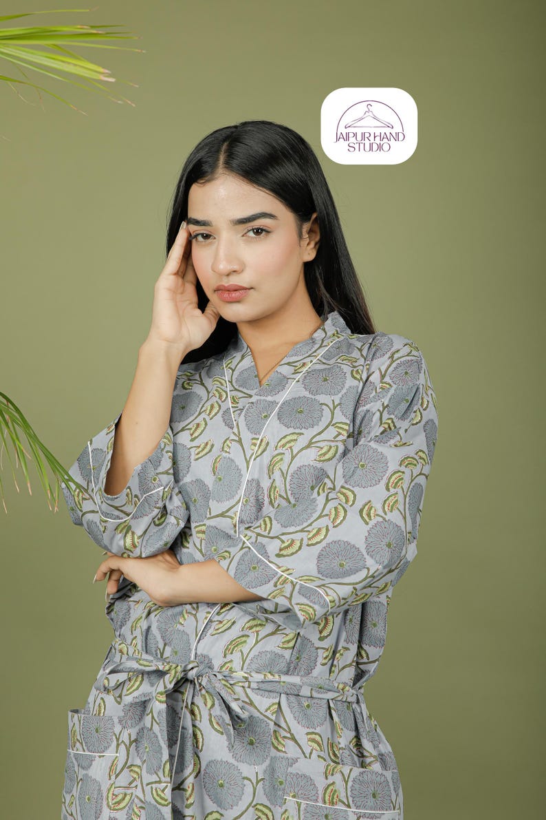 Puede incluir: Bata con estampado floral gris claro con ribete blanco. La bata presenta una cintura anudada y un dise&ntilde;o de cuello en V. El estampado floral incluye flores grises y hojas verdes. La bata est&aacute; hecha de una tela suave y ligera.