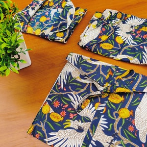May include: A set of three blue and white patterned pajamas with a white bird design. The pajamas feature a long-sleeved top, pants, and a short-sleeved top.