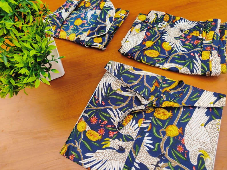 May include: A set of three blue and white patterned pajamas with a white bird design. The pajamas feature a long-sleeved top, pants, and a short-sleeved top.