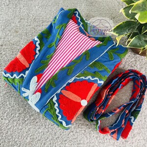 May include: A blue cotton robe with red and green embroidered flowers. The robe has a pink and white striped lining and a matching tie.