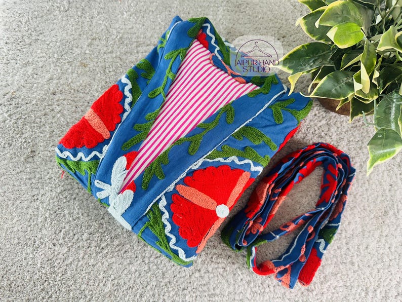 May include: A blue cotton robe with red and green embroidered flowers. The robe has a pink and white striped lining and a matching tie.