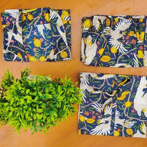 May include: A set of four blue and white patterned pajama tops with a tropical bird design. The fabric has a white background with blue leaves and white birds.
