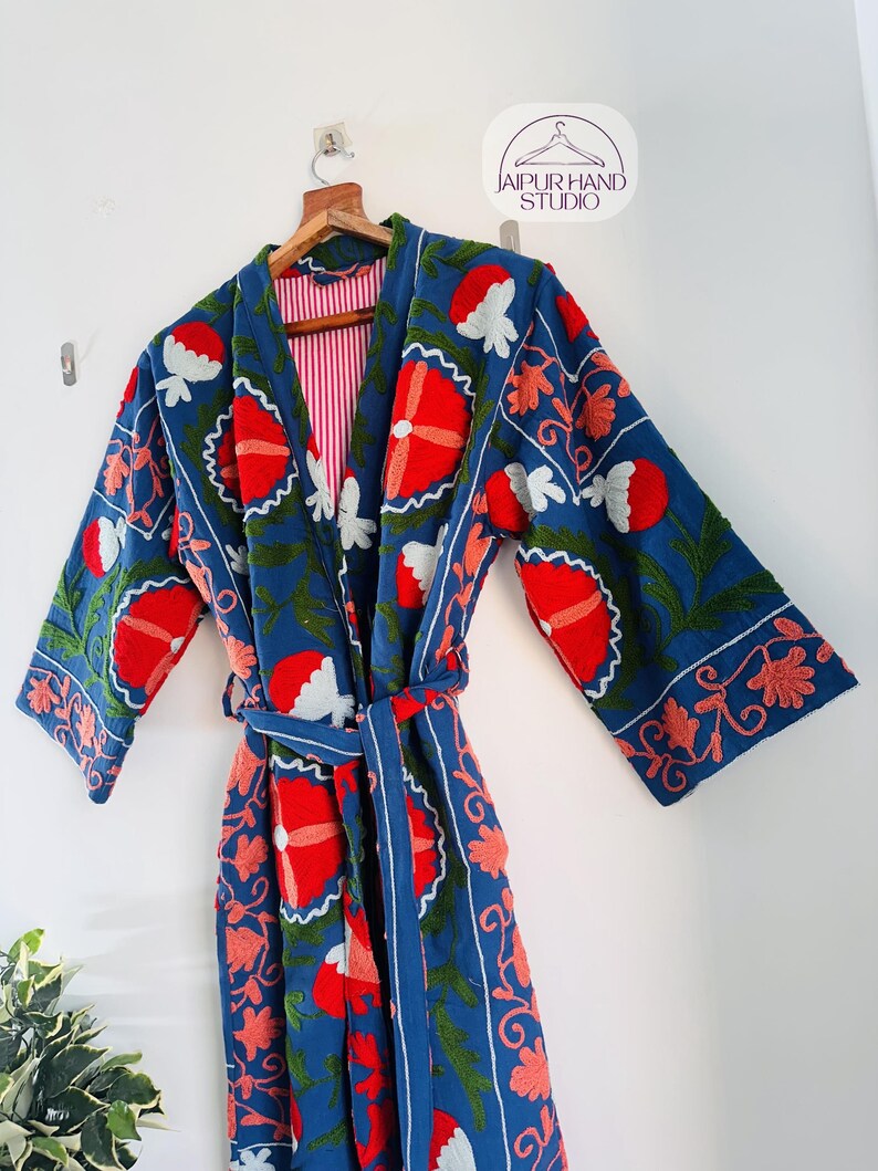 May include: A blue cotton robe with red, white, and green floral embroidery. The robe has a tie belt and long sleeves.