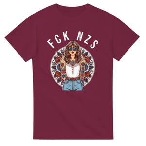 Könnte beinhalten: Ein maroonfarbenes T-Shirt mit einer weißen Grafik einer Frau mit Sonnenbrille und Tattoos, die den Mittelfinger zeigt. Der Text "FCK NZS" befindet sich über dem Kopf der Frau.