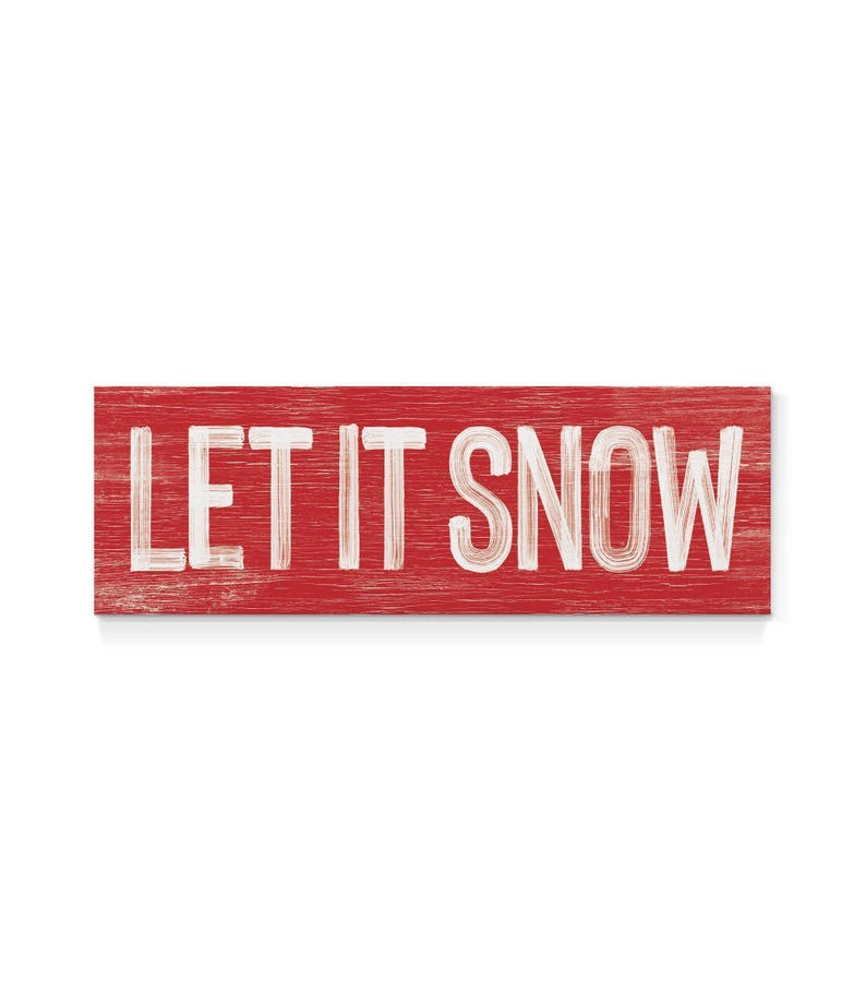 Full view of the barn red "Let It Snow" sign with weathered white lettering on a plain background.