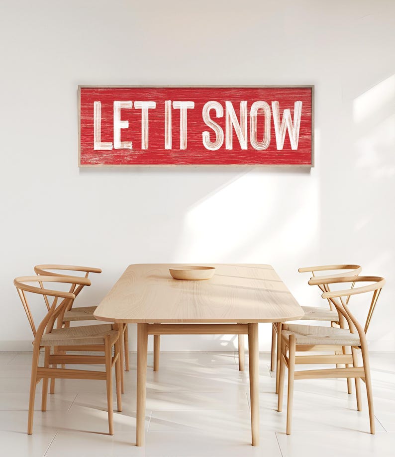 Barn red "Let It Snow" wall print hung above a wood dining table.