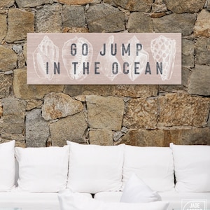 Letrero costero de lona rosa ruborizado con frase "Salta al océano"
