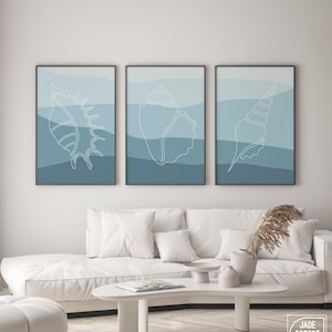 a living room with a white couch and two paintings on the wall