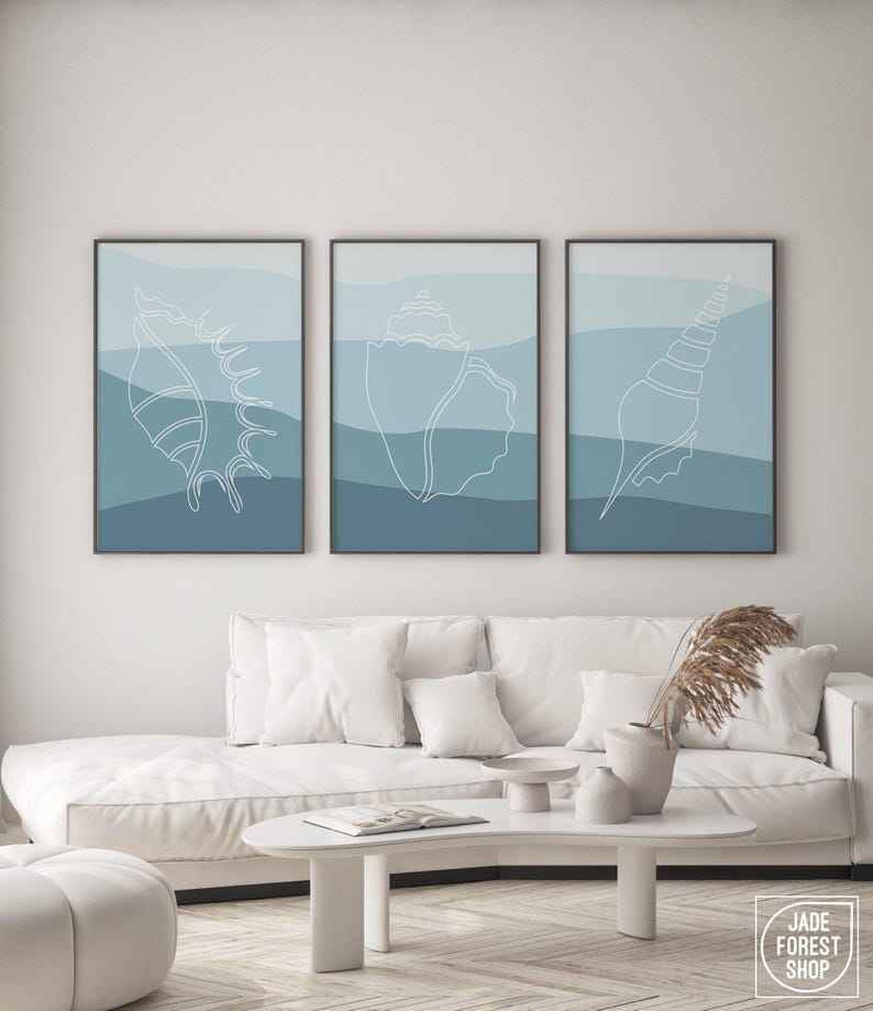 a living room with a white couch and two paintings on the wall