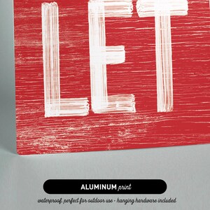Close up of the "Let It Snow" sign printed on aluminum, showing the barn red background and crisp white lettering.