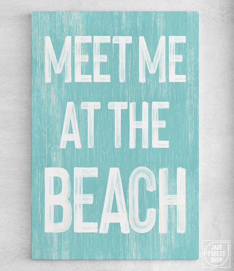 A full view of the teal Meet Me At The Beach sign's complete lettering.