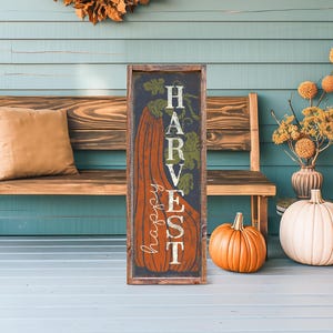 Navy harvest panel with an orange pumpkin propped on teal porch boards beside a wood bench.