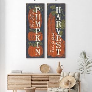 Two tall panels reading pumpkin and harvest hung side by side above a light wood console.