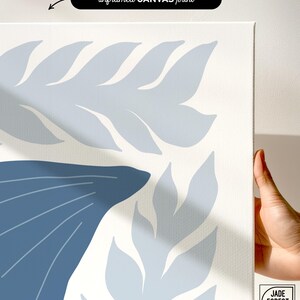A canvas corner of the dusty blue sea creature print set held in one hand, with its woven texture up close.