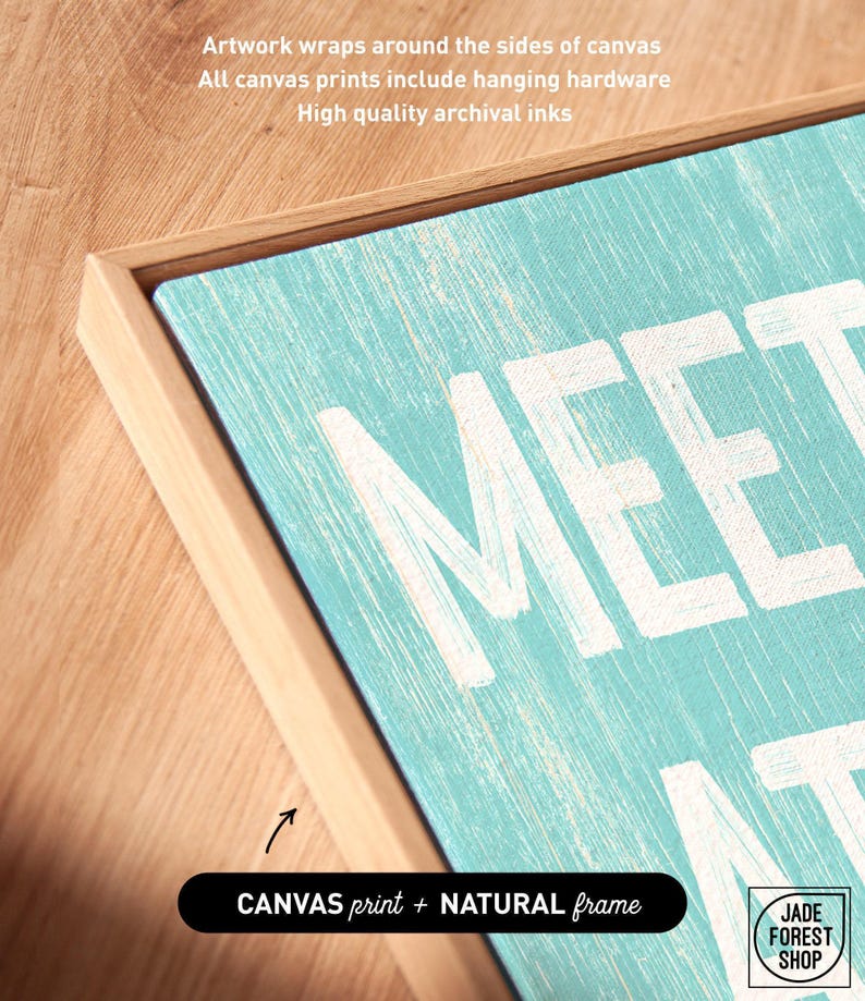 A corner detail of the Meet Me At The Beach sign in a natural wood frame, labeled as the canvas print with natural frame option.