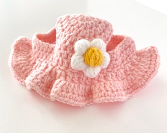May include: A pink crocheted flower-shaped dog collar with a white flower and yellow center.