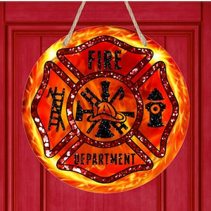 May include: A round, red and black fire department sign with a fire hydrant, axe, and ladder. The sign has a glittery finish and is surrounded by flames.