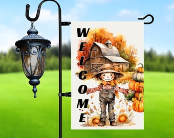May include: A garden flag with a watercolor illustration of a scarecrow in overalls, a barn, and pumpkins. The word "WELCOME" is vertically printed on the flag. The flag is hanging on a black metal garden stake with a decorative lantern.