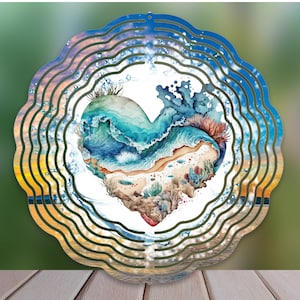 May include: A metal heart-shaped wind spinner with a watercolor design of ocean waves, coral, and sand. The spinner has multiple layers of metal that create a swirling effect when it spins in the wind.